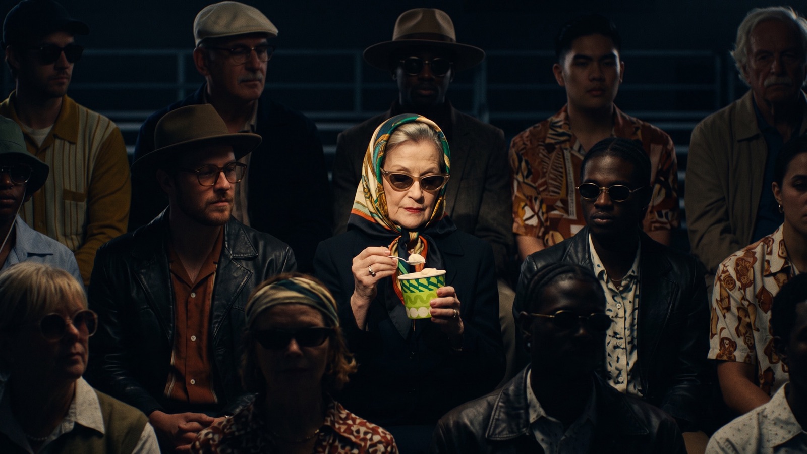 Set: the dark grandstand, rows of spectators who don't react.