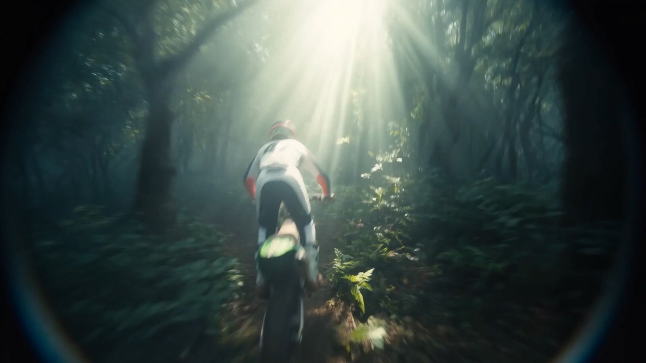Enduro motion study: a forest trail cut through shafts of light.